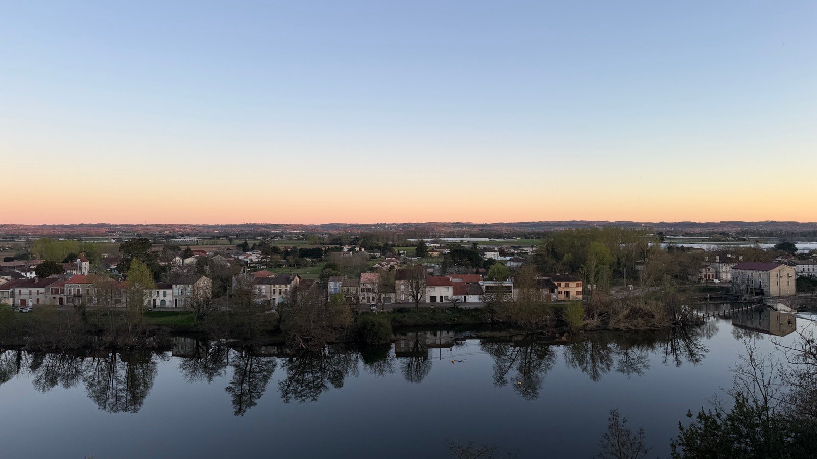 La brume quitte la rive à contre-jour ; le village retient un instant son souffle.